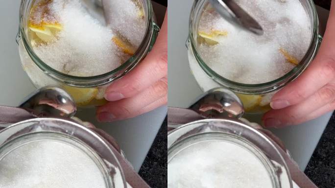 往罐子里的柠檬片上倒砂糖的手的俯视图