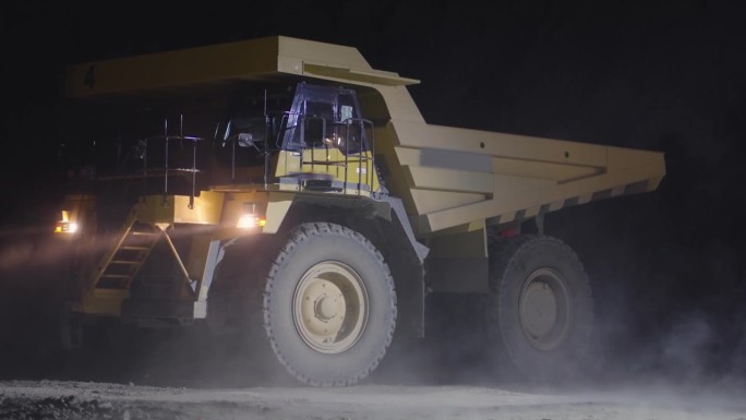 一辆夜间在铜矿运输矿石的自卸卡车扬起的灰尘，慢镜头