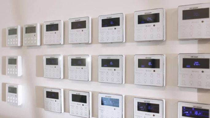 大量办公室气候控制面板的特写。公寓和办公室的空调和供暖控制面板位于白色墙壁上。