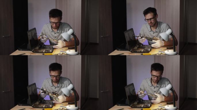 戴眼镜的修理工带着沮丧的神情检查着笔记本电脑的主板。