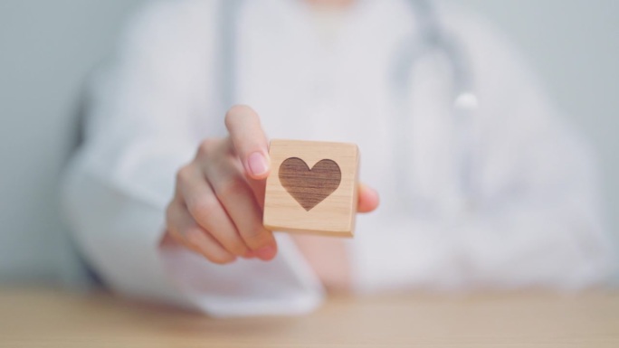 医院里，医生手握心脏形状的积木。爱，捐赠，世界心脏日，世界卫生日，企业社会责任捐赠和保险概念