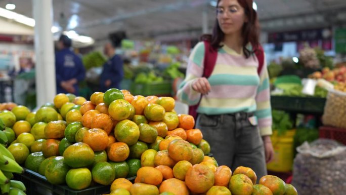 年轻的女顾客在超市挑选水果