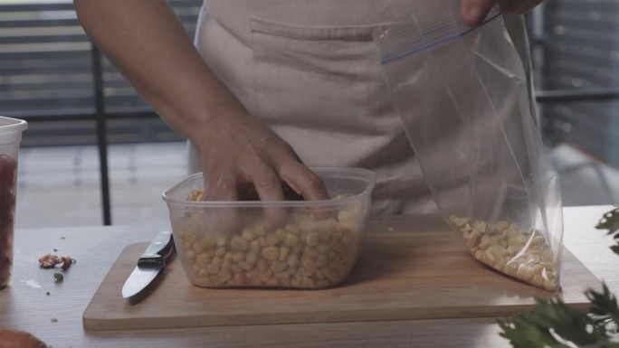 一名妇女在为冬天保存食物时将玉米放入塑料冷冻袋中