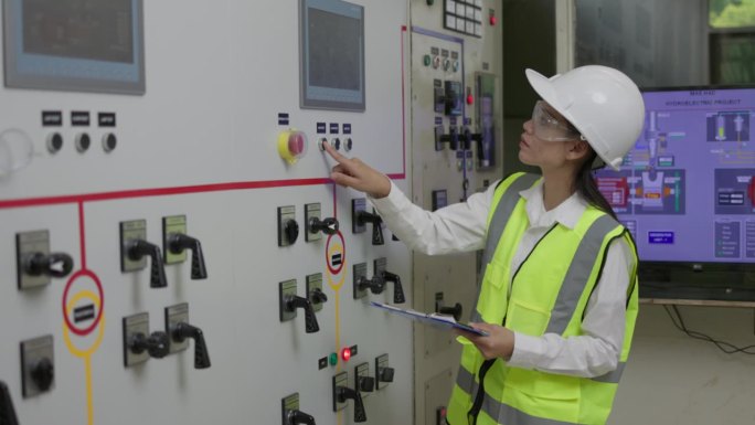 操作员电气工程师妇女在控制面板上的计量和填写报告，电气工程服务工人在控制用电量。