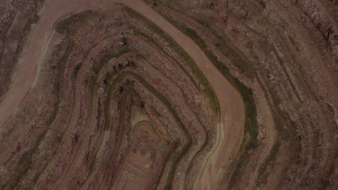 无人机倾斜向下看采石场在英国农村与水从地下深处倾泻现场。彩色土壤层和砾石路没有机械
