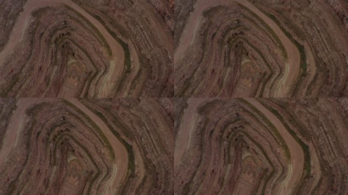 无人机倾斜向下看采石场在英国农村与水从地下深处倾泻现场。彩色土壤层和砾石路没有机械