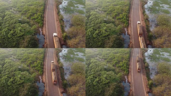 无人机拍摄的一辆卡车在苏格兰湿地和树木旁的土路上行驶的画面