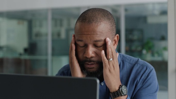 累了，成熟了，是个头疼的黑人，用笔记本电脑收发邮件，处理业务问题或失败。疲劳，倦怠和一个非洲商人偏头