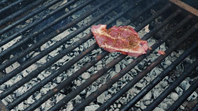 一个人在木炭上准备烤肉。烧烤肉