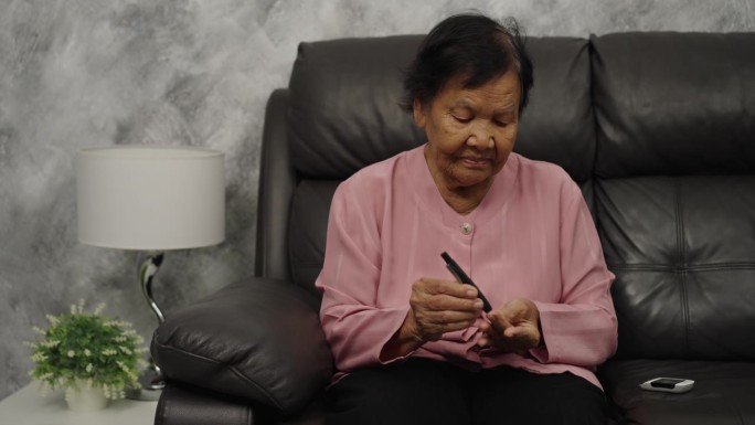 老年妇女在家用血糖仪检查血糖水平。检查糖尿病的概念。