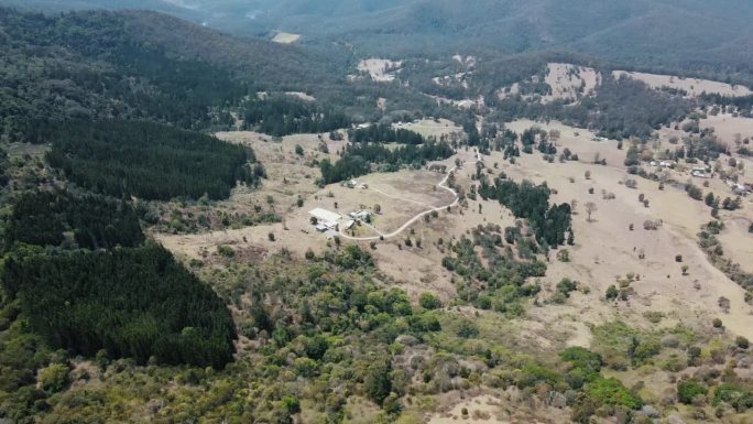 无人机在郁郁葱葱的澳大利亚原生山脉上空飞行，那里的树木已部分被砍伐
