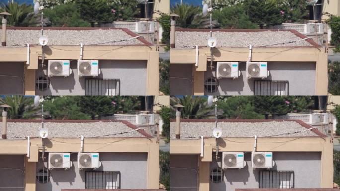 在阳光普照的房子外面，空调通过转动的风扇运转;附近有一个互联网天线，可以对抗室内的热空气。