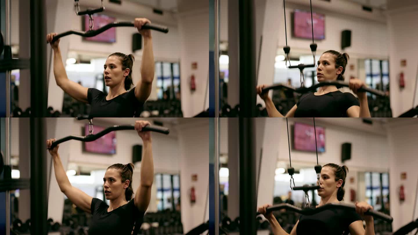三角肌强化:在健身房里，女运动员用专门的器械孜孜不倦地锻炼她的三角肌。
