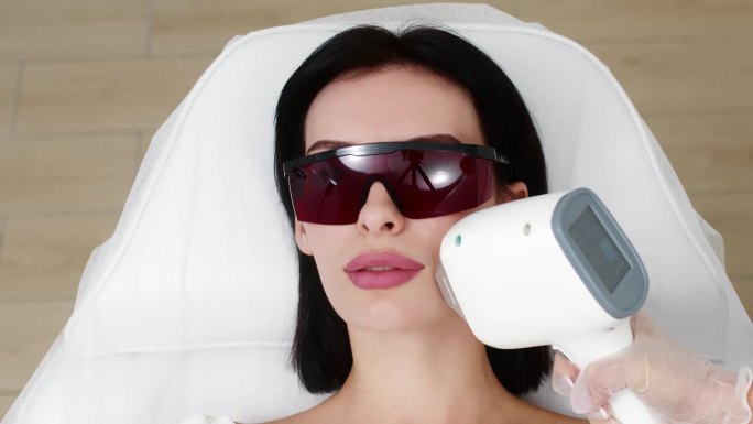 一名妇女正在使用激光进行整容手术。美容诊所的面部护理，改善皮肤状况的广告概念