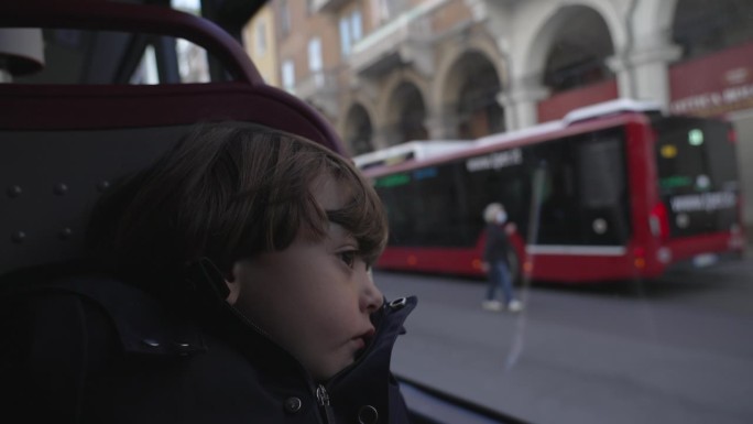 忧伤忧郁的小孩倚在巴士上的玻璃窗上
