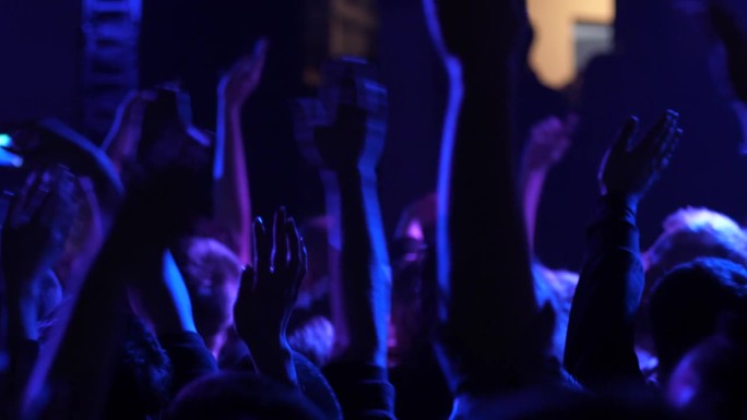 在免费音乐会上，欢呼雀跃的年轻人一边举起手，一边挥手