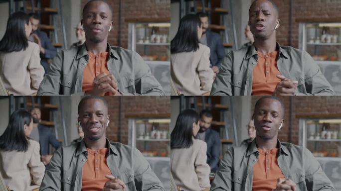 成功的年轻非洲裔美国企业家的肖像，说话和手势，戴着耳机进行在线视频通话