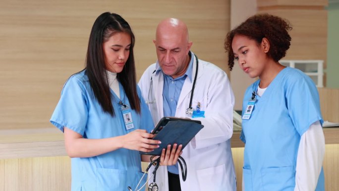 现代医院病房中，资深男医生教授手持剪贴板，与普通女医生一起指导病人治疗。医疗保健和医药