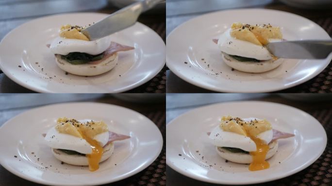 用刀叉切蛋黄吃白盘子里的蛋松饼。在烤面包上切荷包蛋和溏心蛋黄
