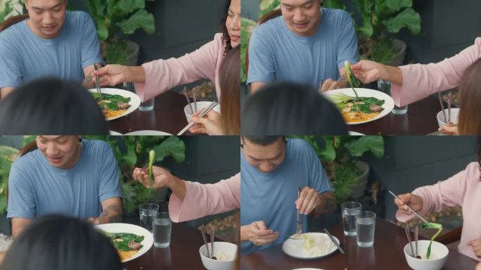 亚洲家庭吃中国菜的特写，坐在后院的餐桌上玩得很开心。多代同堂的家庭一起享受消费。