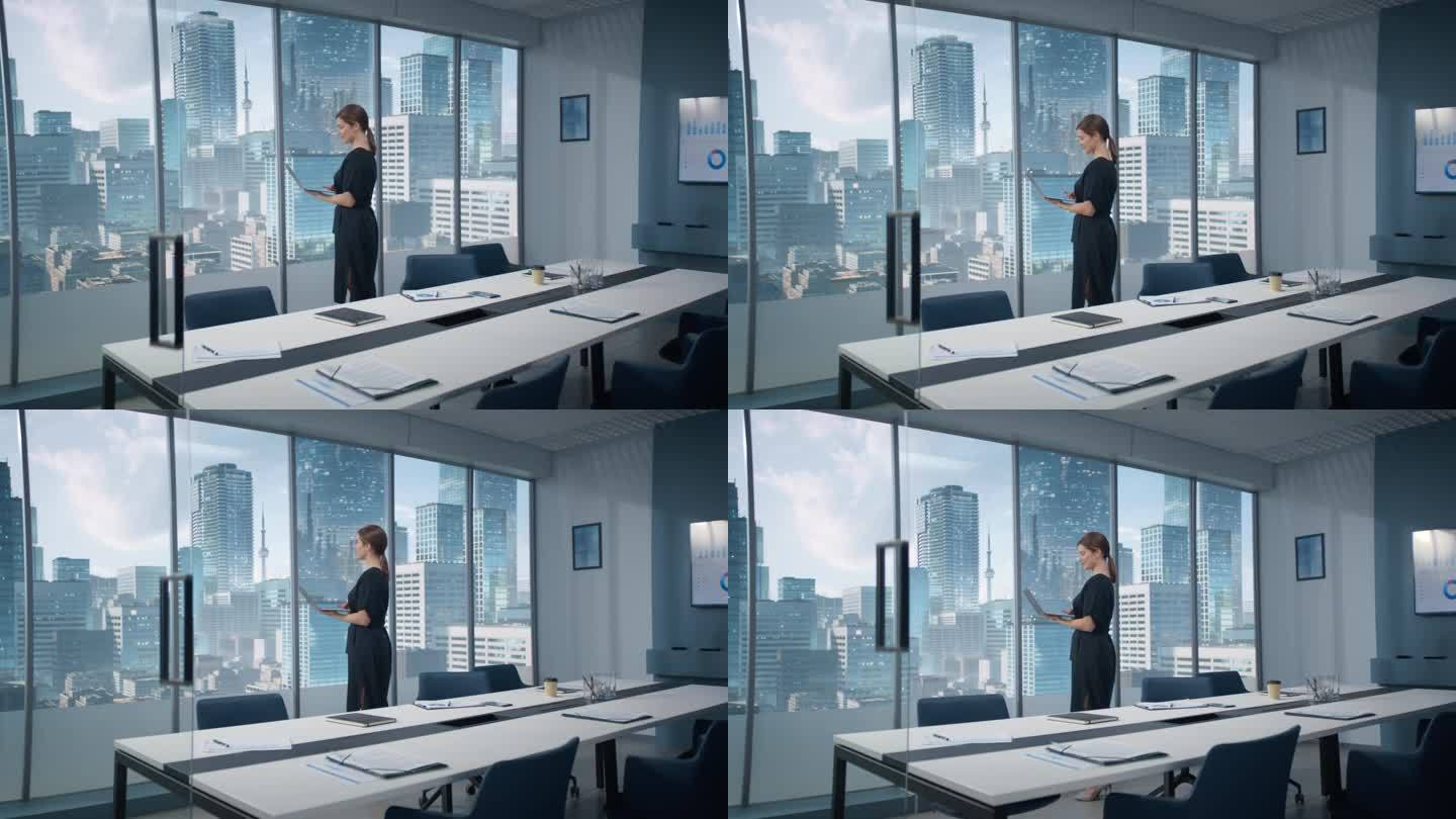 广角白人女商人站在摩天大楼的现代办公室里，使用笔记本电脑。成功的商业经理阅读邮件，检查任务。
