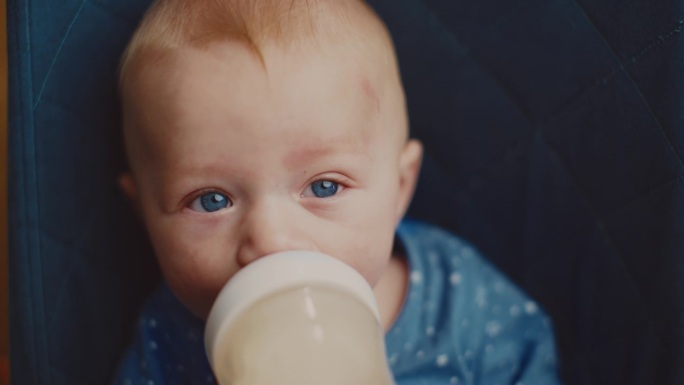 可爱的蓝眼睛小男孩在保镖身上喝牛奶的特写