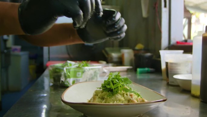 厨师将芝麻菜绿叶最后点缀在海鲜虾面食上，当他们完成时竖起大拇指