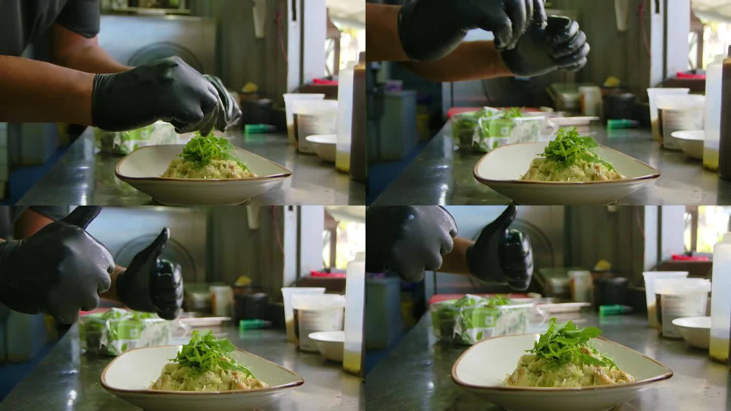 厨师将芝麻菜绿叶最后点缀在海鲜虾面食上，当他们完成时竖起大拇指