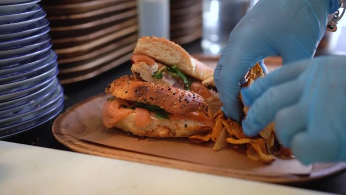 一份鲑鱼百吉饼三明治和薯片已经在厨房里准备好供顾客享用了。