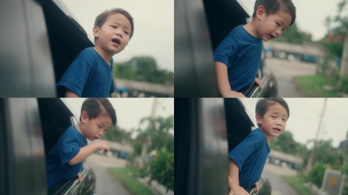 无忧无虑的亚洲孩子在车里玩暑假。在一个晴朗的夏日，小弟弟从车窗里拿出一张滑稽的脸。
