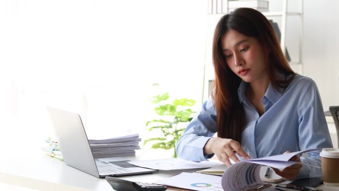 亚洲女性坐在创业公司办公室工作，会计师检查公司财务报表文件，检查财务报表，资产负债表，损益表。审计概