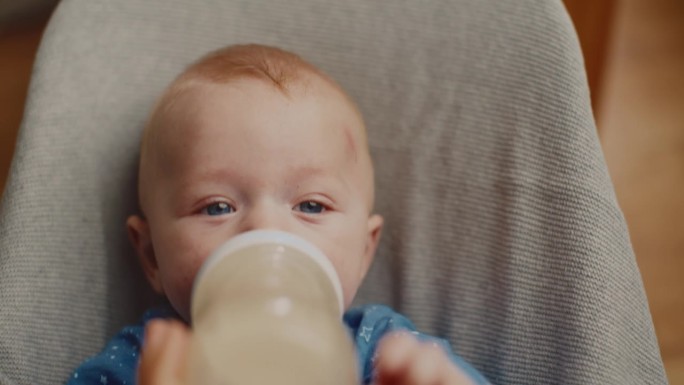《家里的保镖》中可爱的小男孩从瓶子里喝牛奶的高角度肖像