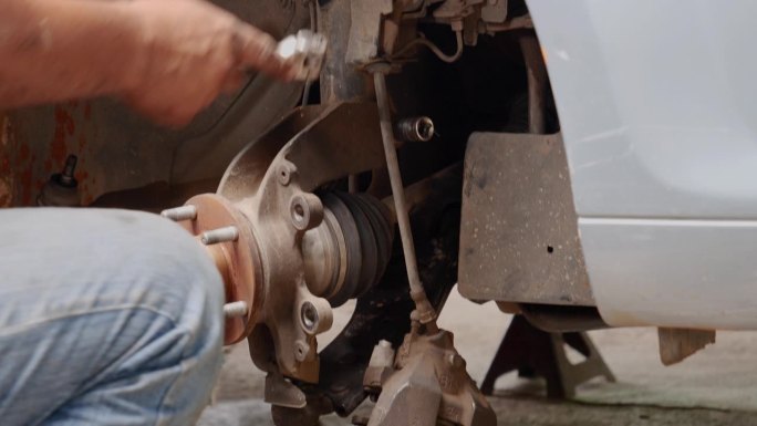 (近景)修车技工正在修车，汽车修理店用千斤顶换轮胎。手动修理减震器机械车辆机械维修。汽车大修维修工程