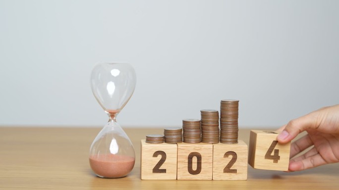 新年快乐，用沙漏和翻转2023变化到2024块。决心，目标，计划，行动，存钱，退休基金，养老金，投资
