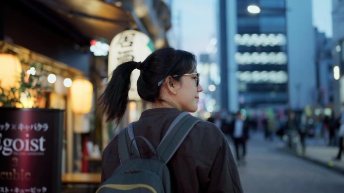 一个放松的亚洲女人带着微笑的后视图在城市度假的乐趣户外生活方式中散步。