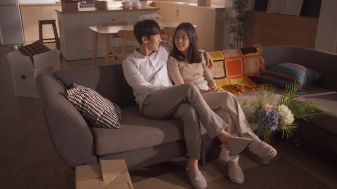 家庭住宅搬进来:幸福的年轻韩国夫妇坐在新买的公寓。女朋友和男朋友搬到一起，谈论他们的未来和他们面前的