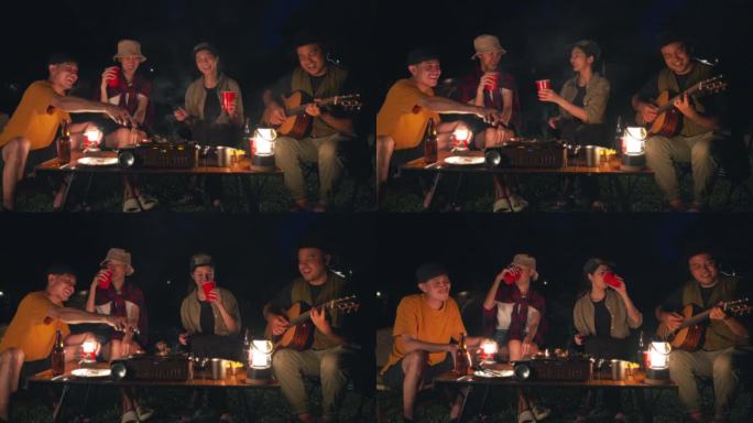 快乐的亚洲多元团体朋友一起喝啤酒。晚上在大自然中露营，他们感到放松和清爽。休闲旅行和户外活动的生活方