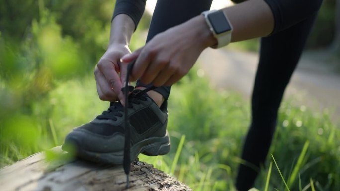 人、手、系鞋带在大自然中健身、跑步或户外运动、远足或徒步旅行。运动员在岩石上系鞋带跑步的特写，准备或