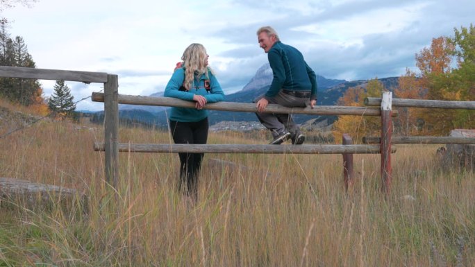成熟的夫妇站在篱笆边欣赏秋天的草地