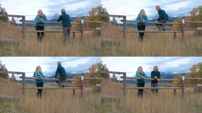 成熟的夫妇站在篱笆边欣赏秋天的草地