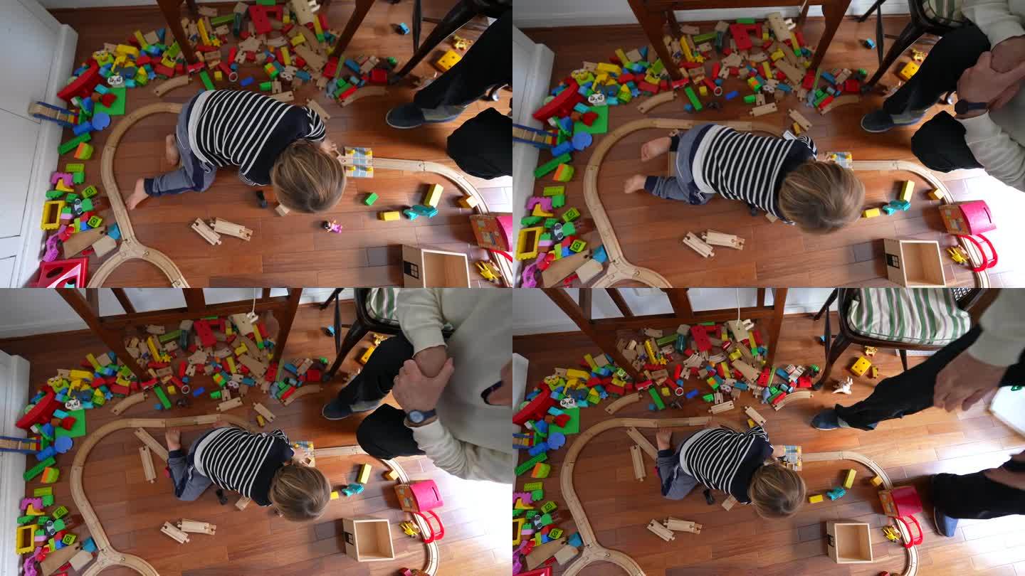 从上面的角度看，小男孩在玩玩具，孩子沉浸在游戏中，复古复古的铁轨和积木散落在周围