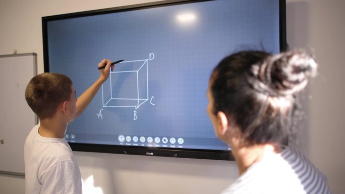 一名白人男生在互动白板上画几何图形，与一名女几何导师进行一对一的教学