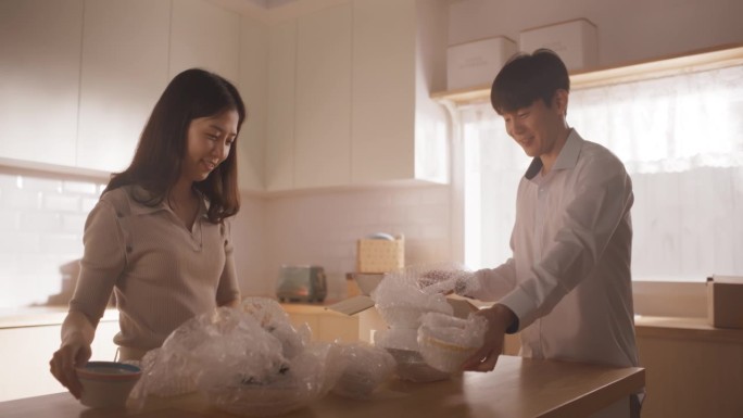 幸福的房主搬进来:可爱的韩国夫妇在他们舒适的新公寓里打开盒子和厨房用具。抵押贷款，房地产，二口之家甜