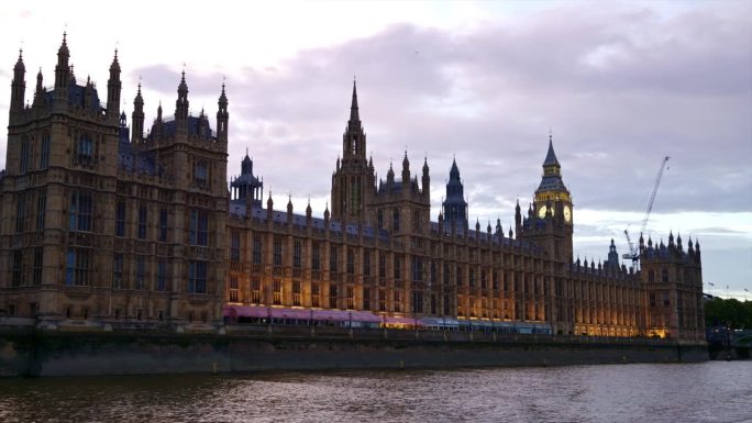 日落时分，从泰晤士河上漂浮的船上俯瞰伦敦，英国。威斯敏斯特宫和伊丽莎白塔