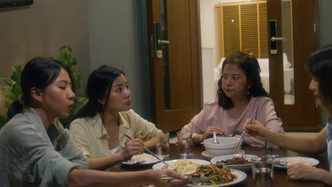 亚洲家庭吃中国菜，晚上坐在家外后院的餐桌上吃晚餐。多代同堂的家庭一起享受消费。