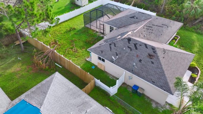 鸟瞰图，飓风伊恩损坏的屋顶覆盖着蓝色防水布防止雨水泄漏，直到更换沥青瓦