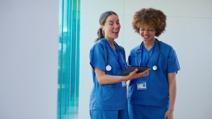 两名女医生穿着手术服拿着电子平板电脑在医院讨论病人的记录