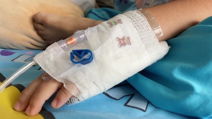 在医院里，一个孩子的手被注射生理盐水的针扎穿了。