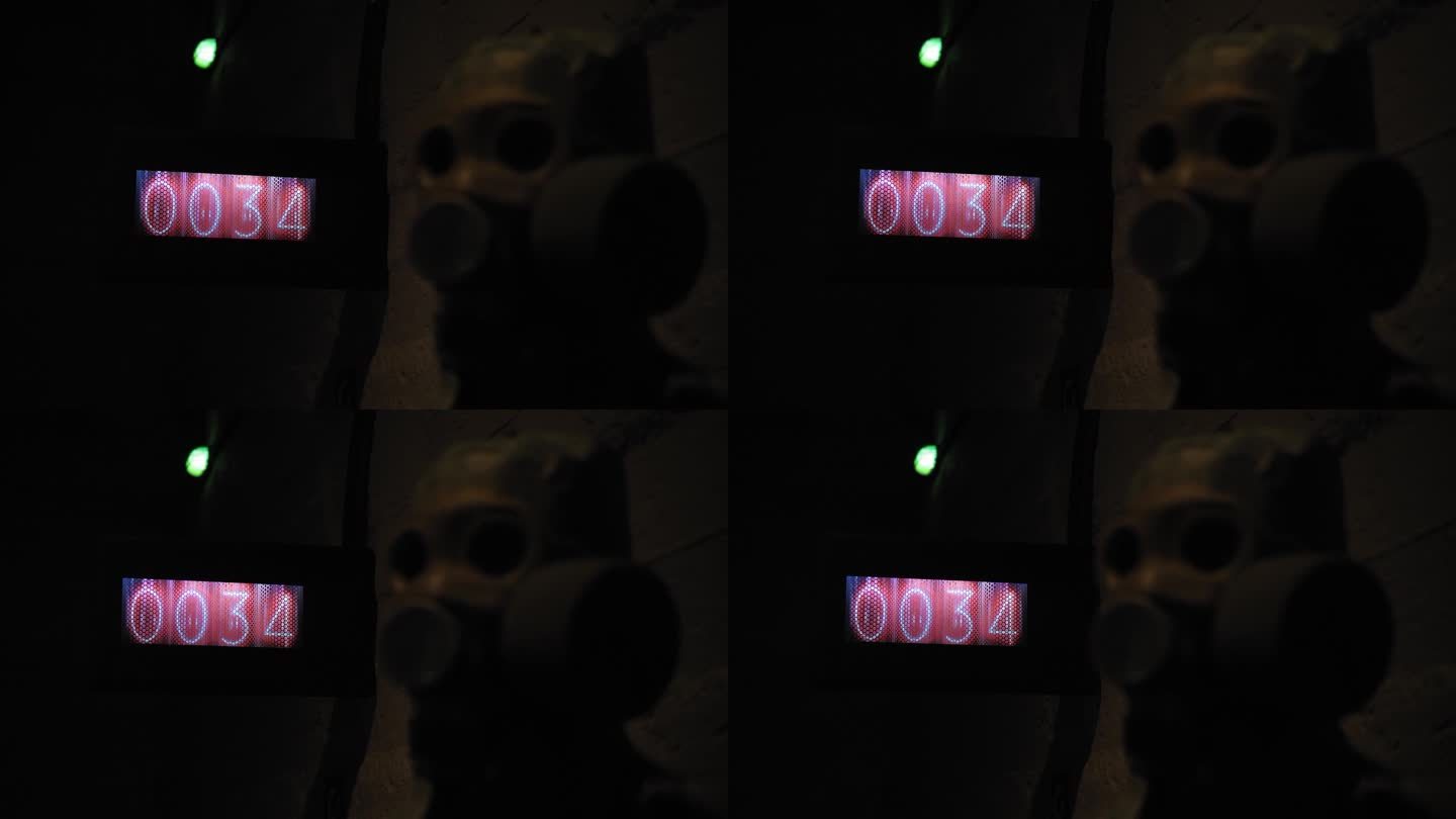 在一个黑暗的防空洞里，一个带有红色数字的秒表和一个防毒面具的特写。