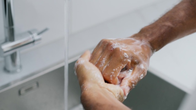 一个人往手上抹肥皂，然后在厨房里洗手